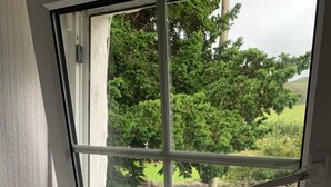 A window with a view of a garden, a welcome sign, and brochures on the windowsill. - Littletown Farm Guesthouse (Keswick)