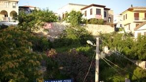 A residential area with a stone wall, a sign for 'Satilik' property, and a 'Royal Apart Hotel' sign. - Vural Apart Hotel (Cesme)
