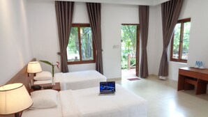 Habitación de hotel con dos camas, un escritorio y una computadora portátil sobre una cama.