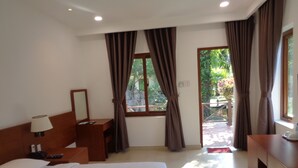 Habitación de hotel con cama, mesita de noche, lámpara y ventana con cortinas.