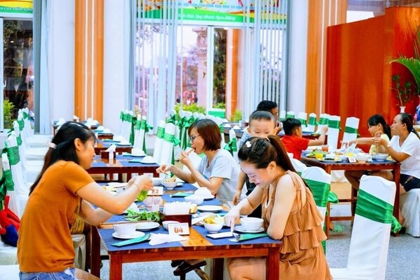 Comedor con mesas y sillas, gente sentada a comer.