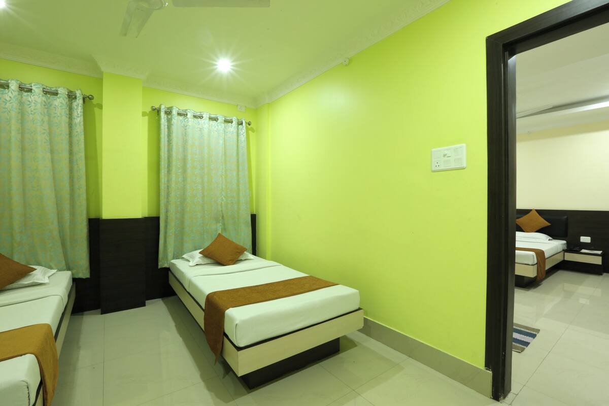 A hotel room with two single beds, a nightstand, a mirror, and a door leading to another room.