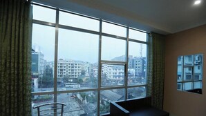 A room with a large window, a sofa, a small table, and a chair. - Hotel Grand Luit (Guwahati)