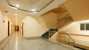 A hotel corridor with a marble floor, a staircase with metal railings, and a ceiling with recessed lighting. - Hotel Grand Luit (Guwahati)
