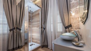 Un baño moderno con cabina de ducha de vidrio, un lavabo con un recipiente decorativo y una pared de piedra.