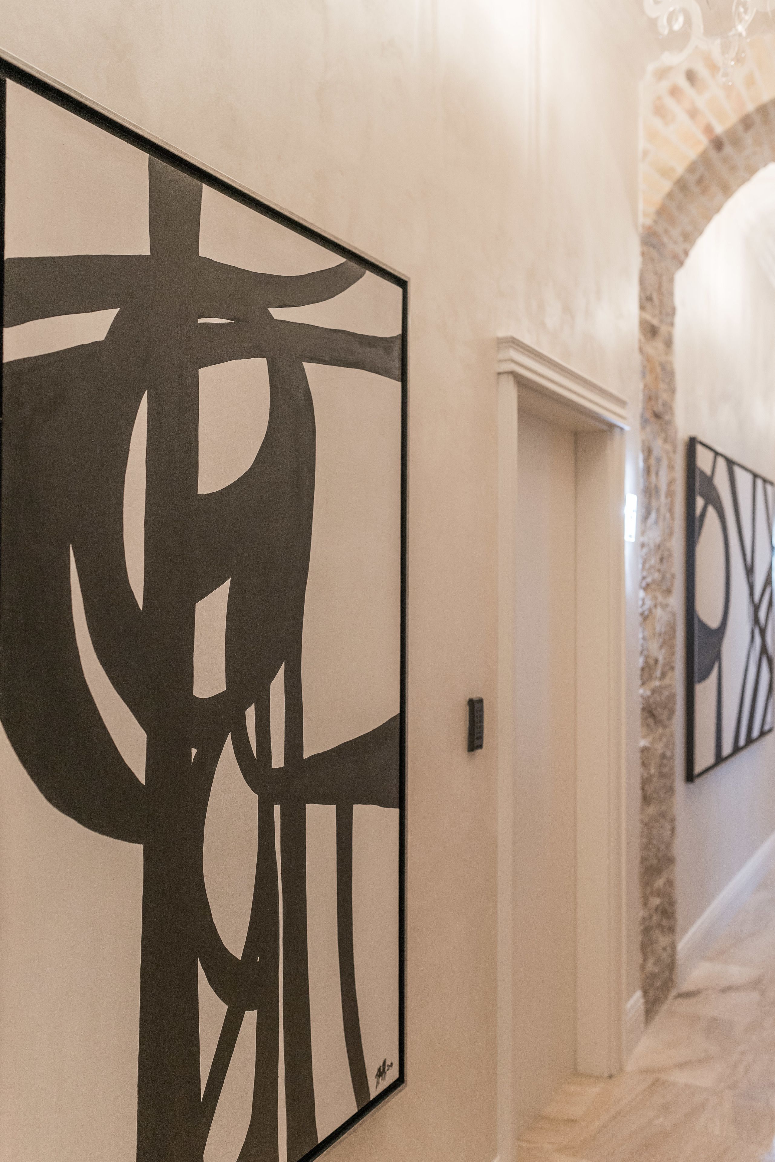 A hallway with abstract wall art and a stone archway.