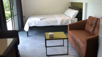 Une pièce comprenant un lit, un canapé en cuir marron, une petite table et une chaise.