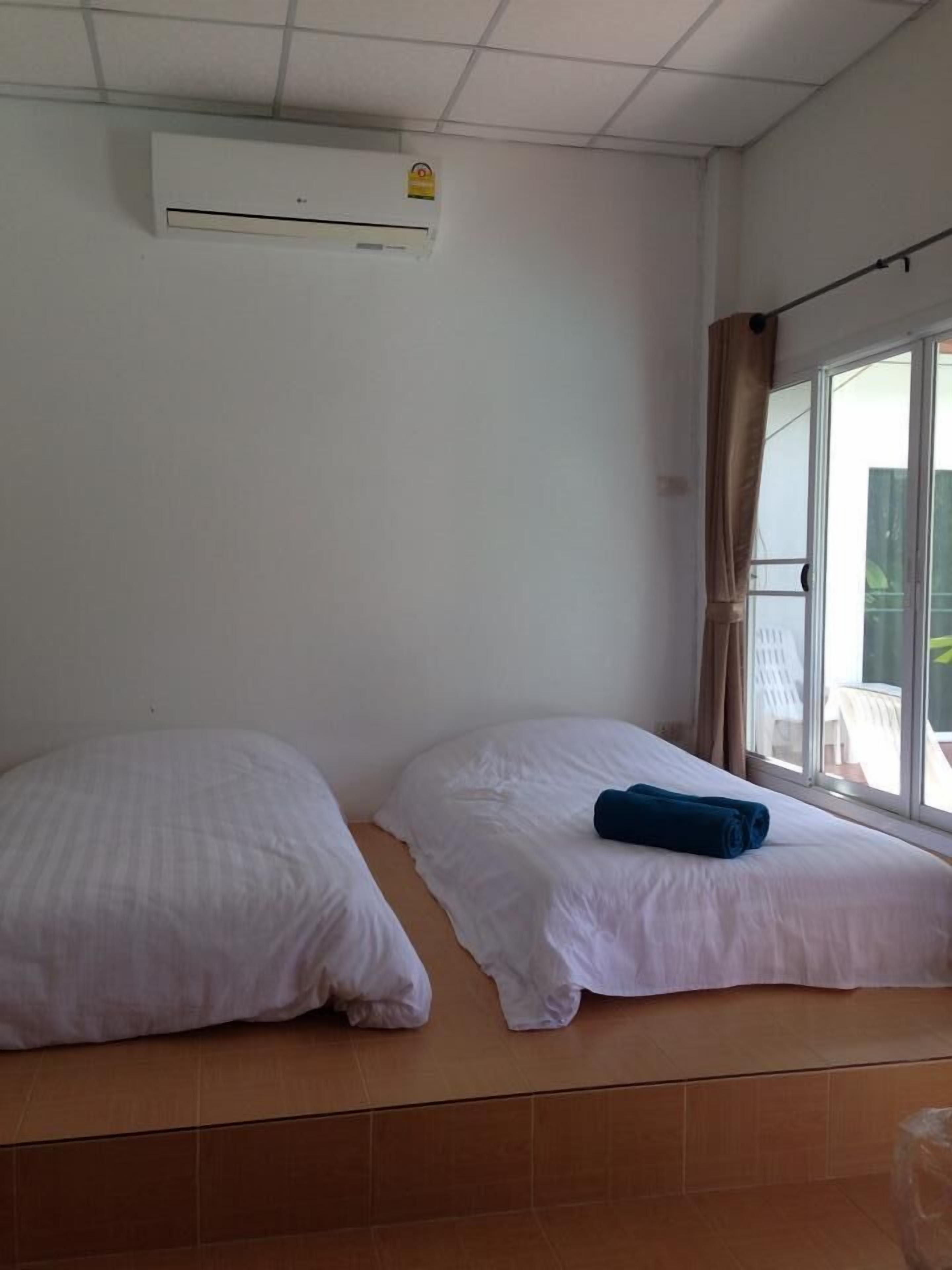 Une chambre d’hôtel avec deux lits, une fenêtre avec des rideaux et un climatiseur fixé au mur.
