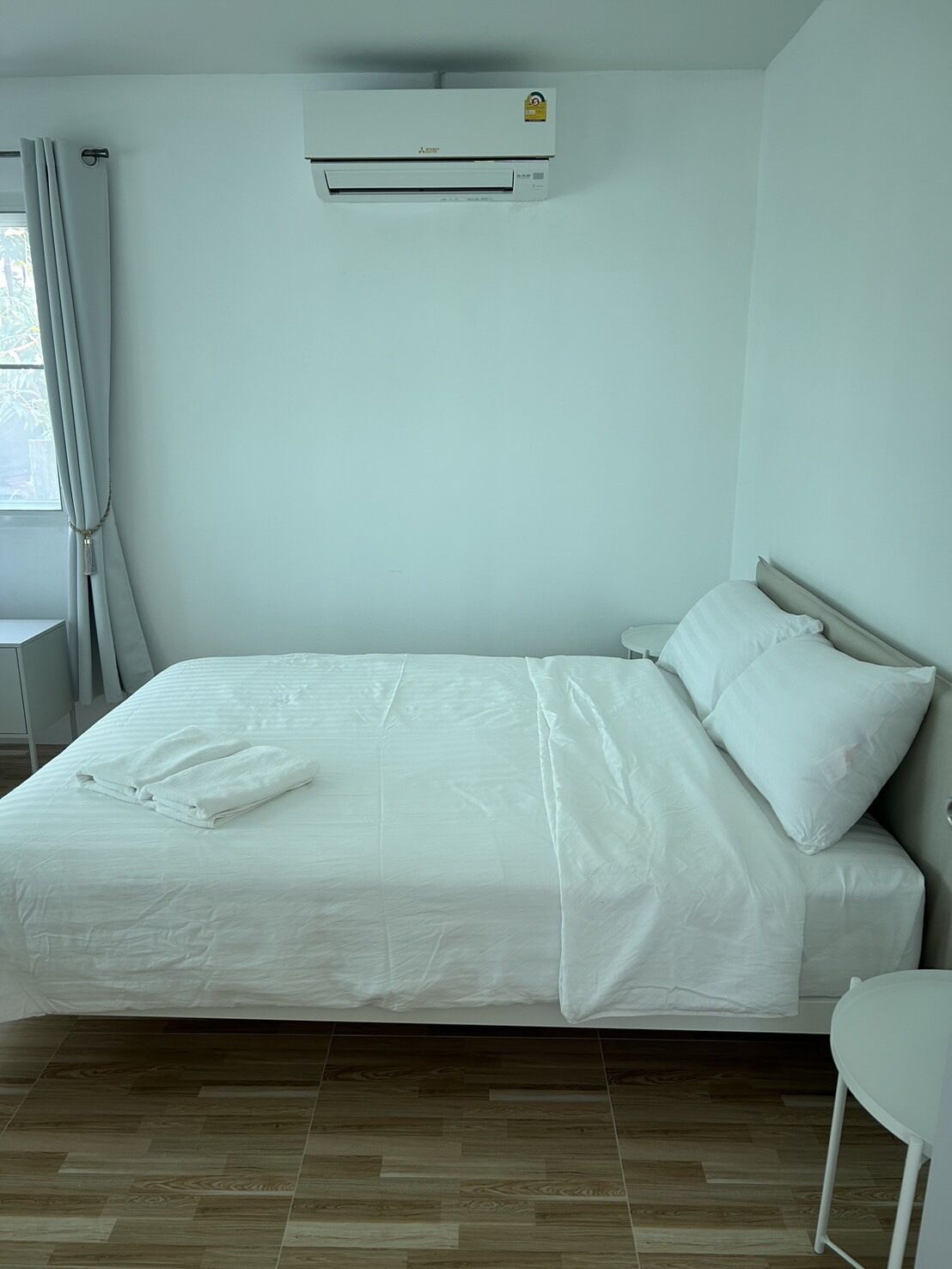 Ein Hotelzimmer mit Bett, kleinem Tisch und einer Wandklimaanlage.