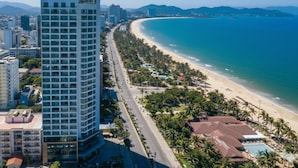 A high-rise hotel with a beach view, a long promenade, and palm trees. - Comodo Nha Trang Hotel (Nha Trang)
