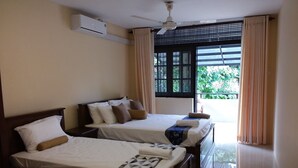 A hotel room with two beds, a ceiling fan, an air conditioning unit, and a view of greenery outside. - Colombo Residence - Luxury House - B & B (Colombo)