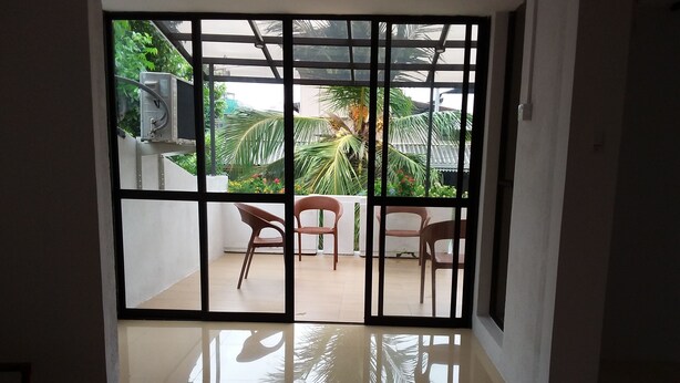 A room with a large sliding glass door leading to an outdoor patio with chairs and a table. - Colombo Residence - Luxury House - B & B (Colombo)