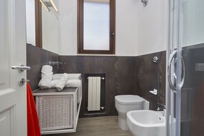 A modern bathroom with a white sink, a white toilet, a glass shower enclosure, and a large mirror above the sink. - Villa Tari' (Castellammare del Golfo)
