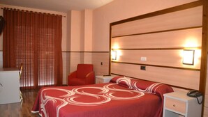 A hotel room with a bed, a desk, a chair, and a nightstand with a phone. - Hotel Pio XII Jumilla (Jumilla)