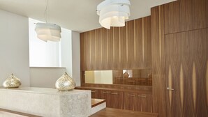Une cuisine moderne dotée d’un plan de travail en marbre, de meubles en bois et de luminaires suspendus.