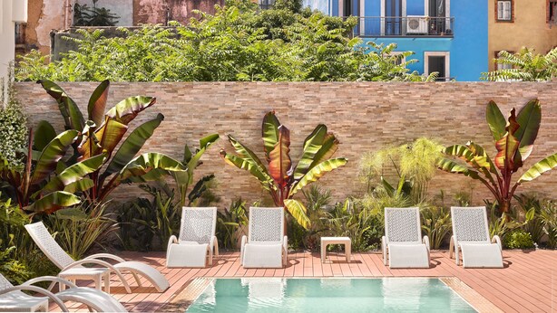 Un espace piscine avec des chaises longues blanches et un mur en briques.