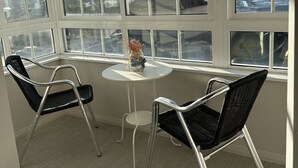 A room with a large window, two chairs, a small table, and a decorative vase.