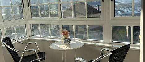 A room with a large window, two chairs, a small table, and a decorative vase.