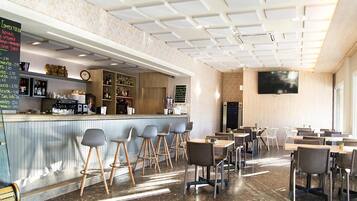 Un café moderne doté d’un bar, de tables et d’un écran de télévision.