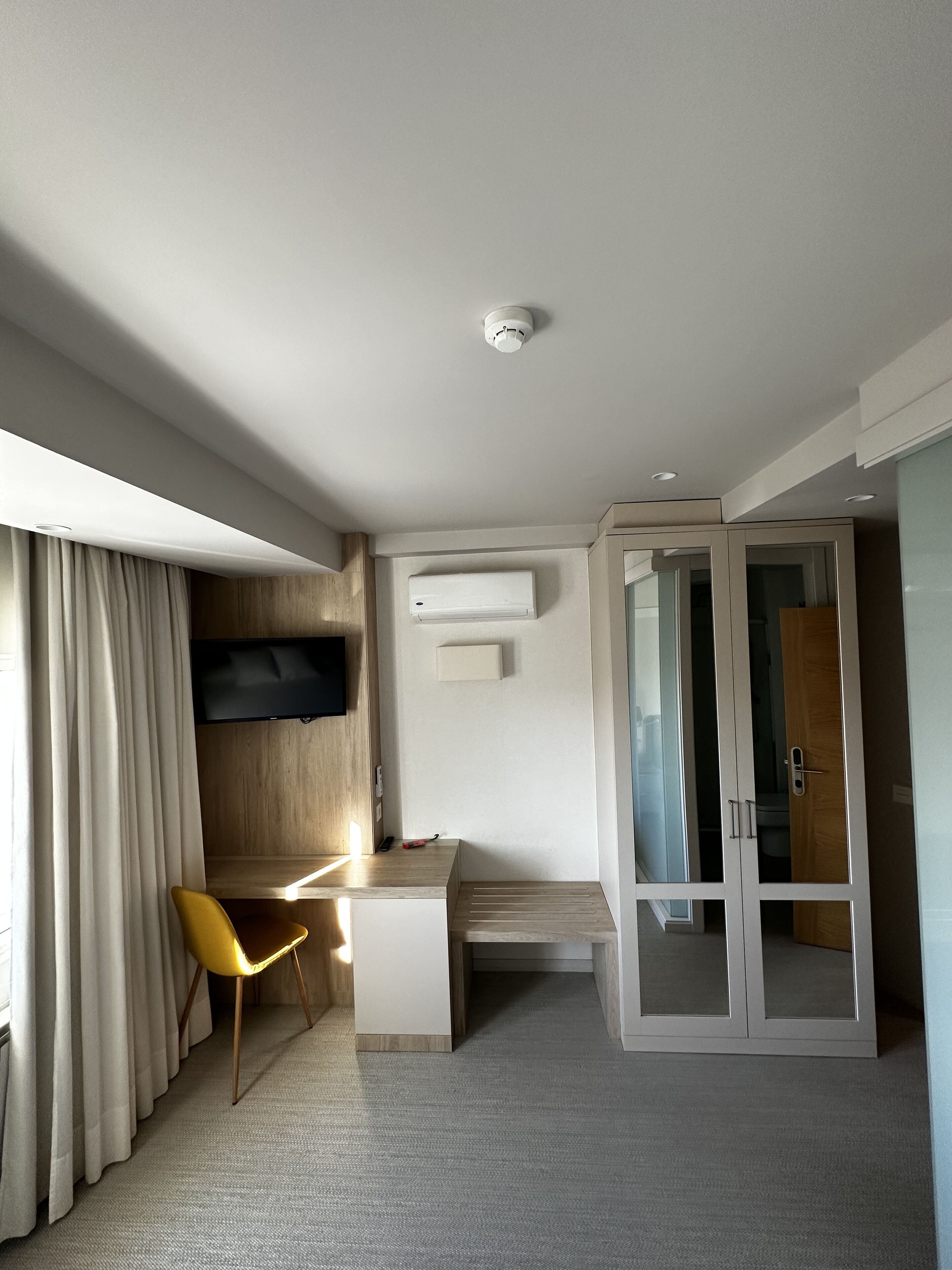 Een moderne hotelkamer met een bureau, stoel en garderobe.