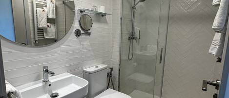 A modern bathroom with a glass-enclosed shower, a sink, and a toilet.