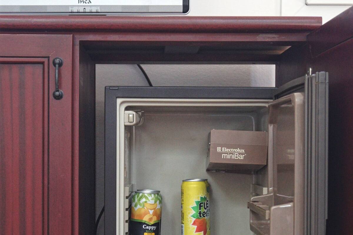 A compact refrigerator with a shelf containing various beverages including canned drinks and a box labeled "Electrolux miniBar".