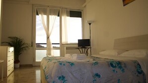 A bedroom with a bed, a TV, a desk, and a window with curtains. - MyRoom CenterStation (Bologna)