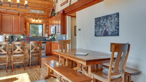 A wooden interior with a dining table, benches, and wooden chairs. There is a kitchen area with cabinets and a microwave. - Access to Rocky Mtn Nat'l Park: Grand Lake Cabin (Grand Lake)