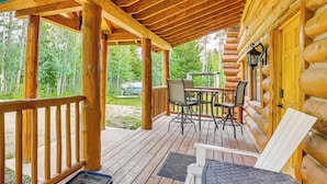 A wooden deck with a table and chairs, surrounded by log cabin walls and a wooden railing. - Access to Rocky Mtn Nat'l Park: Grand Lake Cabin (Grand Lake)