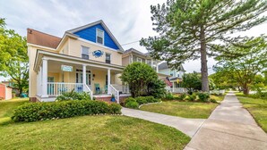 Une maison à deux étages avec un porche, un toit bleu et une enseigne sur laquelle on peut lire « Coin douillet ».