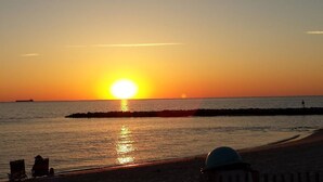 Un coucher de soleil sur une plage, avec une jetée qui s’avance dans l’eau.