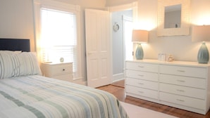 A bedroom with a bed, a dresser, a nightstand, and a mirror. - Coastal Charmer, Fire Pit & Two Blocks to Beach (Cape Charles)
