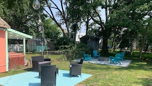 A backyard with outdoor furniture, a stone fire pit, and a pergola. - Coastal Charmer, Fire Pit & Two Blocks to Beach (Cape Charles)