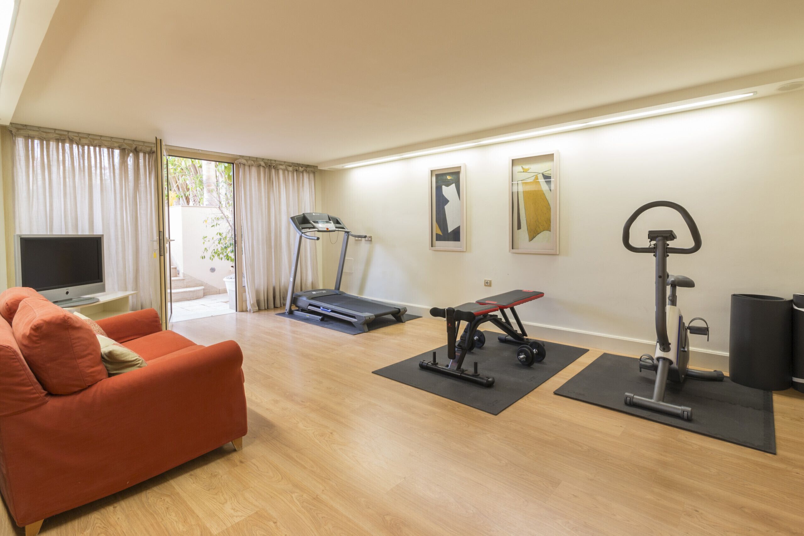 A living room with a treadmill, exercise bike, and a sofa.