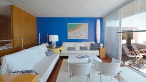 Ein modernes Hotelzimmer mit einem weißen Sofa, zwei weißen Stühlen, einem kleinen Tisch, einer Lampe und einem Bild an der Wand.