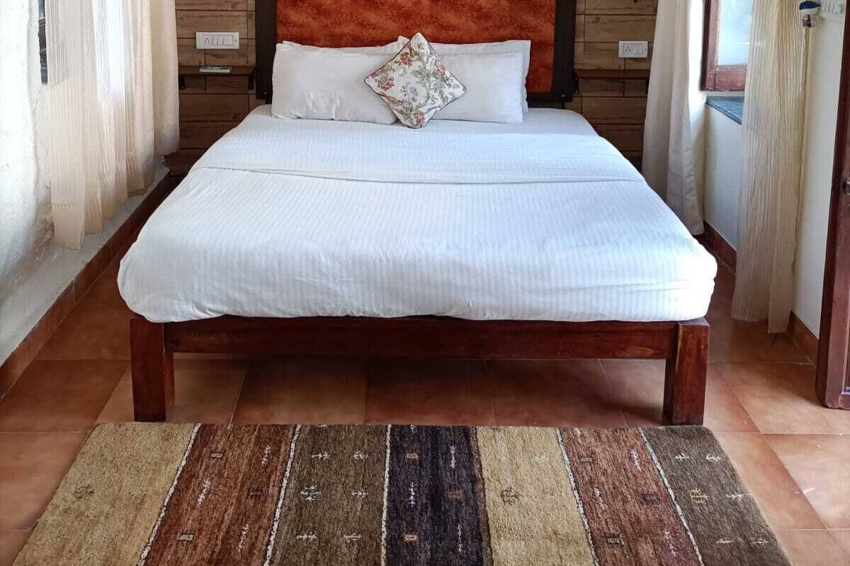 A bedroom with a wooden headboard, a bed with white bedding, and a wall-mounted air conditioner.