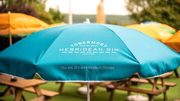 Un paraguas azul con el texto "Tobermory Hebridean Gin" y "El Arte del Destilador Hebridense".