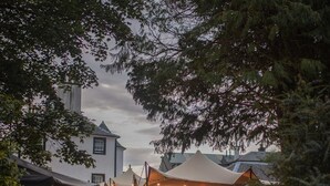 An outdoor market with tents and tables, surrounded by trees and buildings. - The George Hotel (Inveraray)