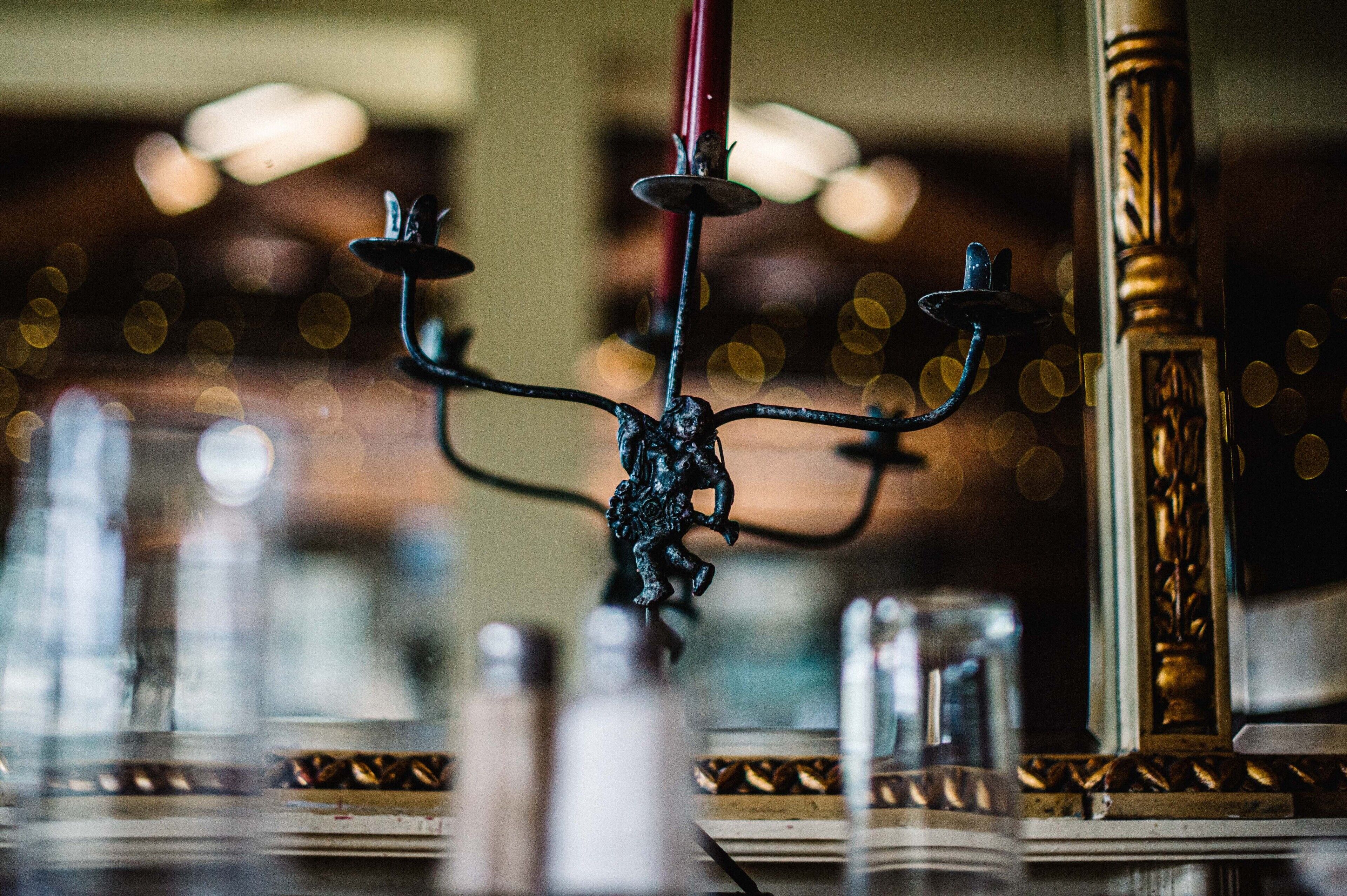 A chandelier with a decorative figure, a mirror, and a table with various items.
