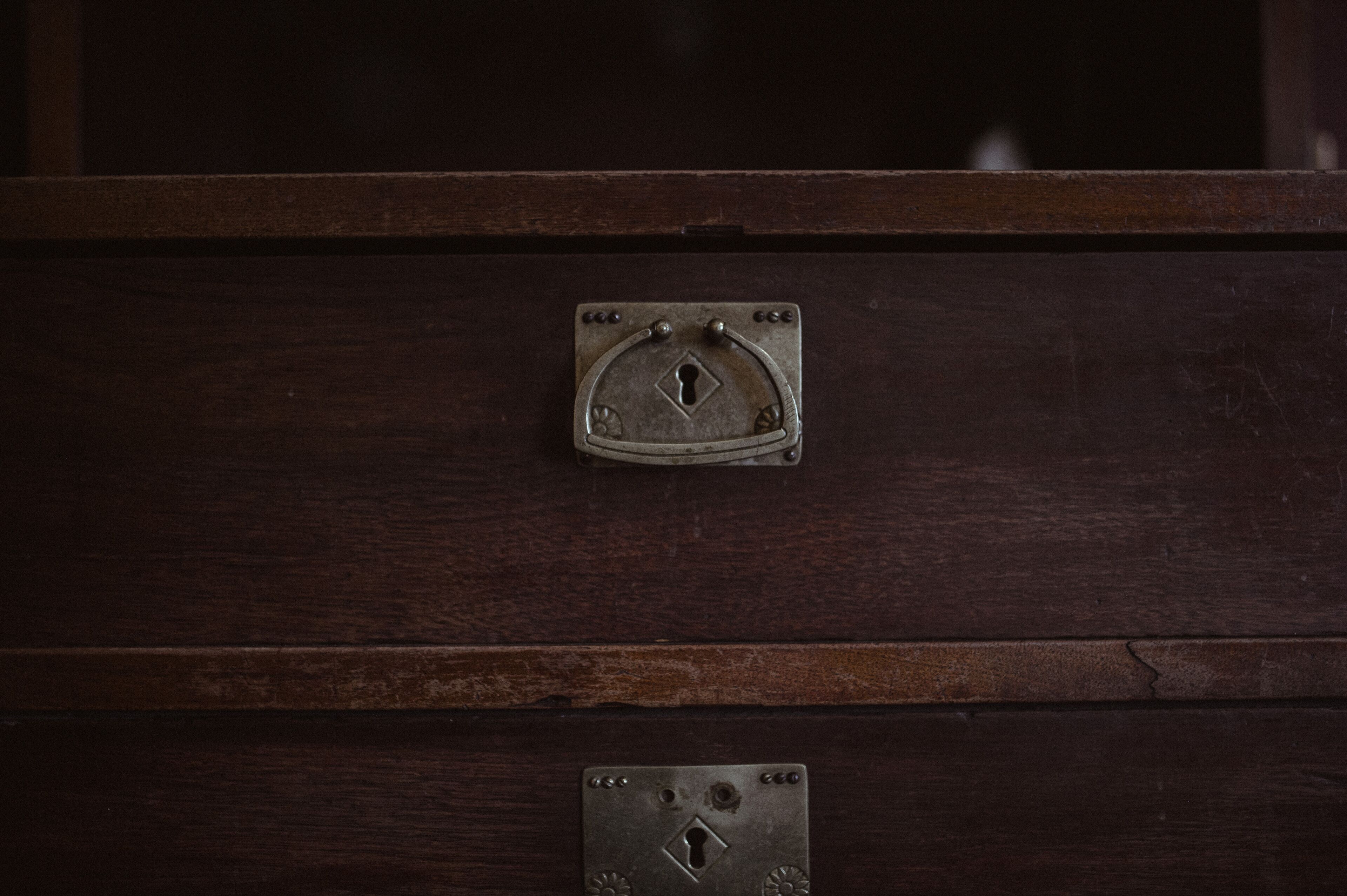 A dark wooden cabinet with a metal latch and a keyhole.