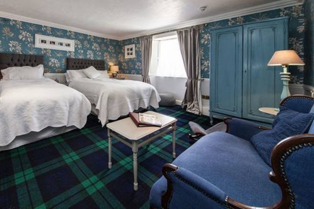 A hotel room with two beds, a blue sofa, a small table, and a blue cabinet.