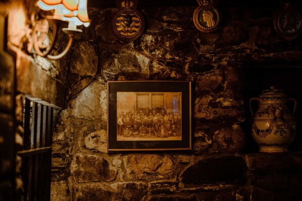 A stone wall with a framed photograph, a decorative plate, and a ceramic jug.