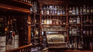 A bar with shelves stocked with various liquor bottles and glasses. - The George Hotel (Inveraray)
