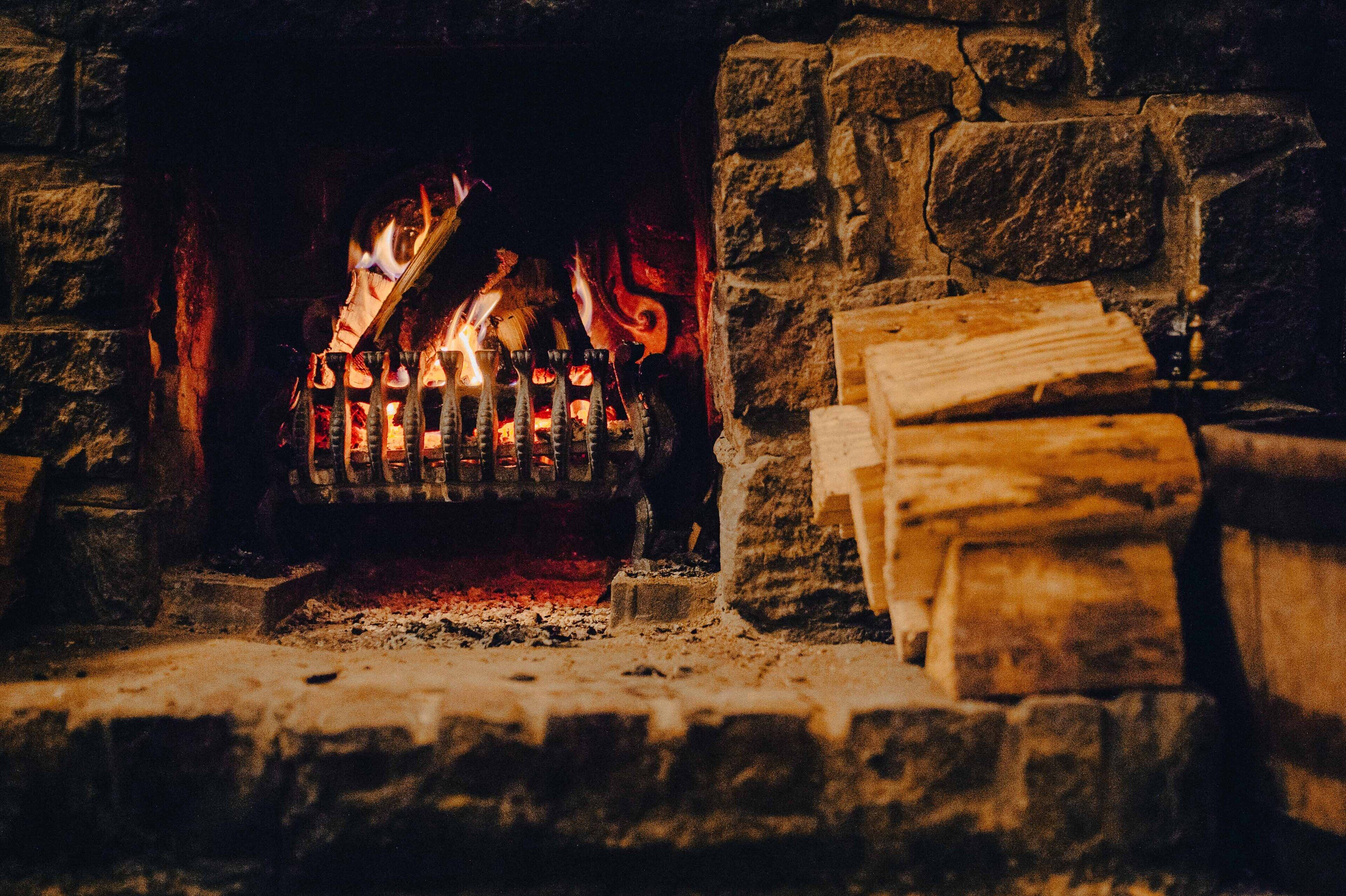 Une cheminée en pierre avec des bûches et un feu qui crépite à l’intérieur.