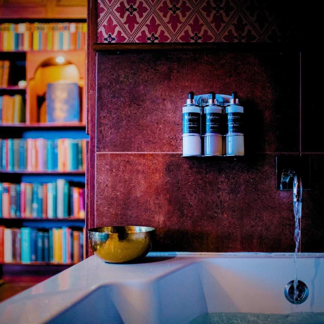 A bathroom with a bathtub, a shelf with toiletries, and a bowl.