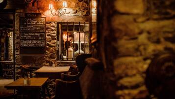 En hyggelig restaurant med stenvægge, en menutavle og en varm indretning.