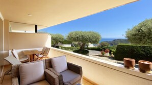 Ein Balkon mit Korbmöbeln, Meerblick und Kübelpflanzen.