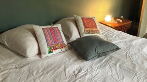 A bed with white bedding and decorative pillows, a bedside table with a lamp, and a framed picture on the wall. - House with garden in the city center (Marseille)