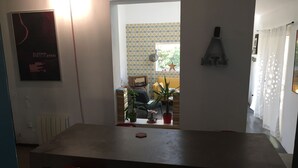 A dining area with a table and four chairs. There is a poster on the wall and a lamp on the wall. - House with garden in the city center (Marseille)