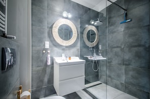 Un baño moderno con dos lavamanos, un espejo, ducha y perchero para toallas.